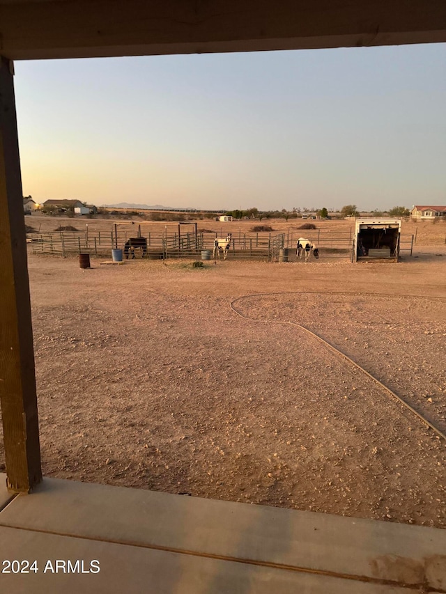 yard at dusk featuring a rural view