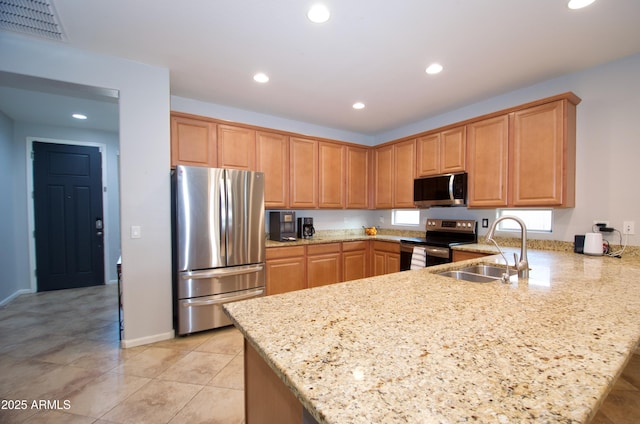 kitchen featuring appliances with stainless steel finishes, light stone countertops, light tile patterned floors, sink, and kitchen peninsula