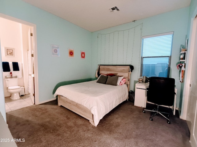 bedroom with connected bathroom and dark carpet