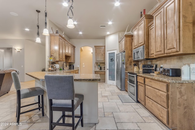 kitchen featuring decorative backsplash, sink, pendant lighting, a breakfast bar, and stainless steel appliances