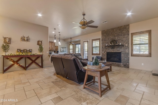 living room featuring ceiling fan and a stone fireplace