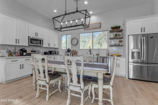 kitchen featuring stainless steel appliances, white cabinetry, light hardwood / wood-style flooring, and decorative light fixtures