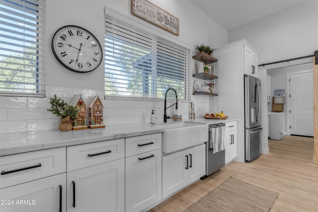 kitchen featuring sink, stainless steel appliances, white cabinetry, and a barn door