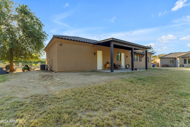 rear view of house featuring a patio area, cooling unit, and a lawn