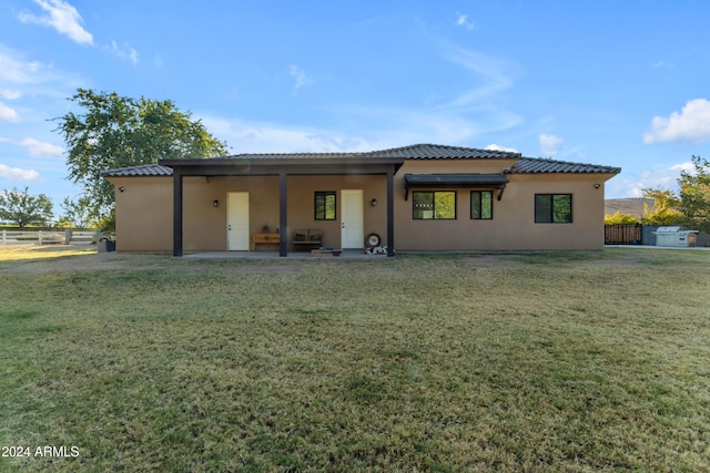 back of property with a lawn and a patio