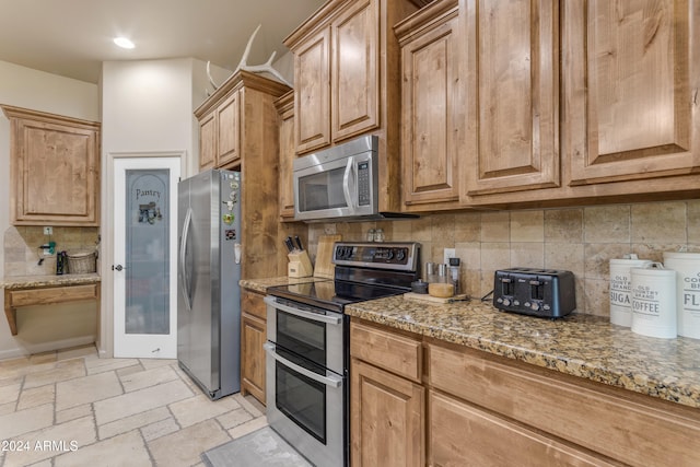 kitchen featuring light stone counters, decorative backsplash, and stainless steel appliances