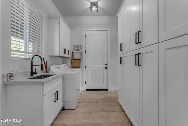 laundry area featuring cabinets, sink, independent washer and dryer, and light wood-type flooring