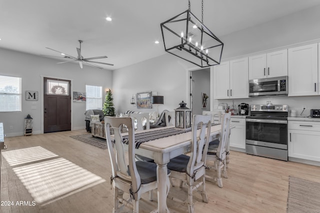 dining area with ceiling fan with notable chandelier and light hardwood / wood-style floors