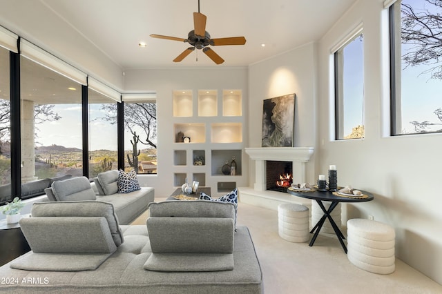 living room with built in shelves, ceiling fan, and plenty of natural light