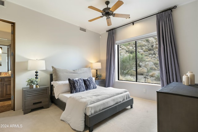 bedroom featuring multiple windows, ensuite bathroom, ceiling fan, and light colored carpet