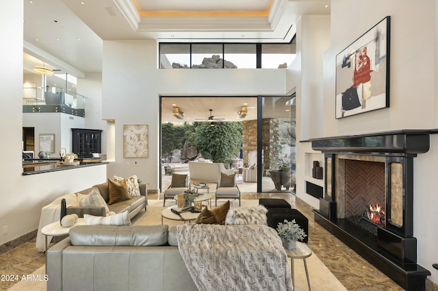 living room with ceiling fan, a high ceiling, and a tray ceiling