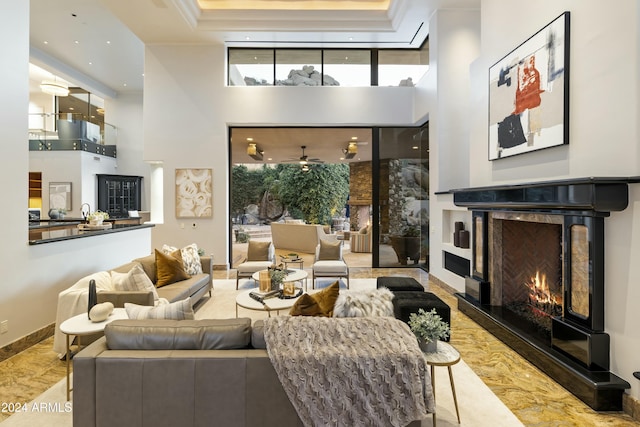 living room with a fireplace, a high ceiling, and ceiling fan