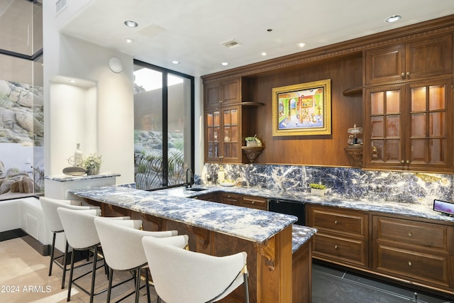 bar with backsplash, dark tile patterned flooring, sink, light stone countertops, and a wall of windows