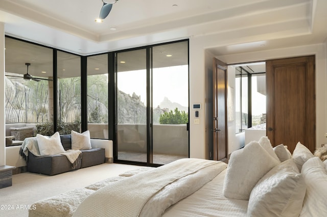 carpeted bedroom featuring a tray ceiling, access to exterior, and a mountain view