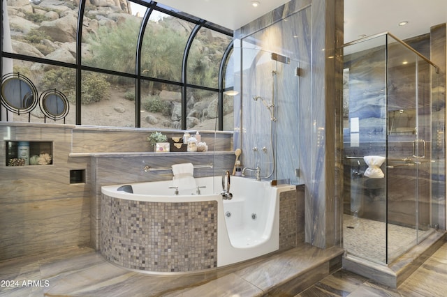 bathroom with separate shower and tub, plenty of natural light, and tile walls