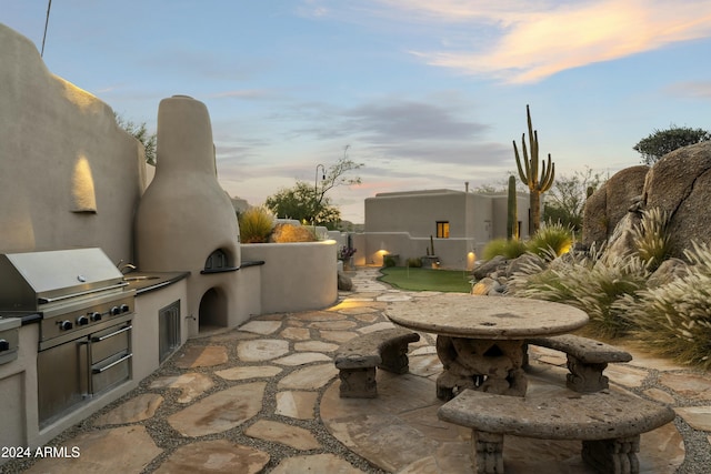 patio terrace at dusk with area for grilling and exterior kitchen