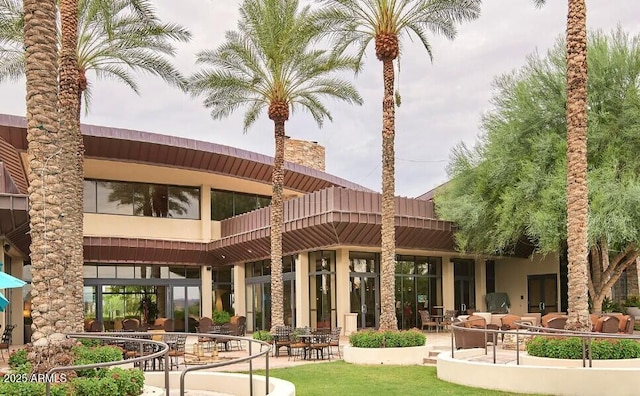 rear view of house with a chimney, a patio area, and stucco siding