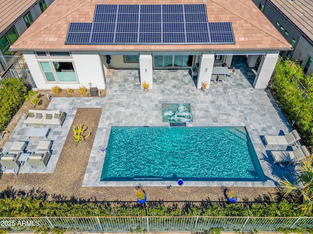 back of property with a fenced backyard, roof mounted solar panels, and a patio