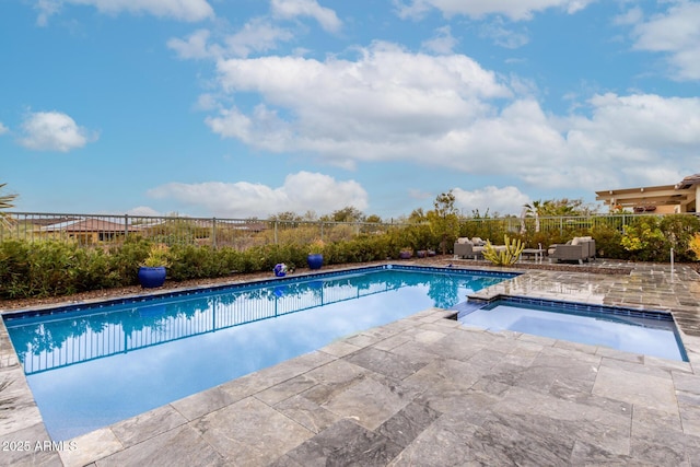 view of swimming pool featuring a patio area, fence, and a pool with connected hot tub