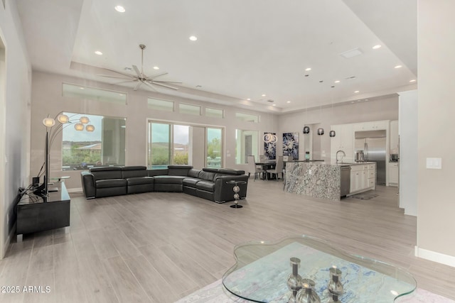 living area featuring light wood-style flooring, baseboards, a ceiling fan, and recessed lighting