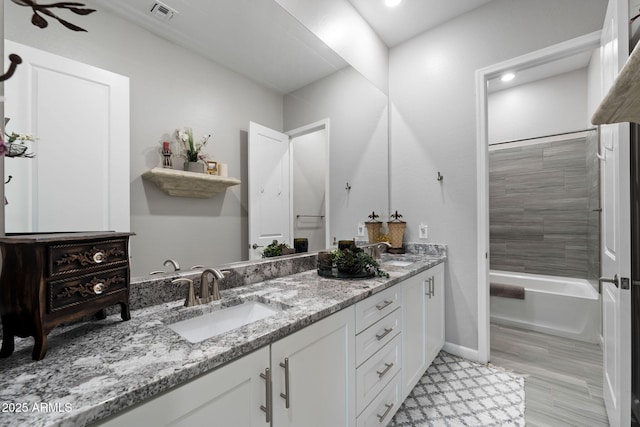 full bath featuring tub / shower combination, visible vents, a sink, and double vanity