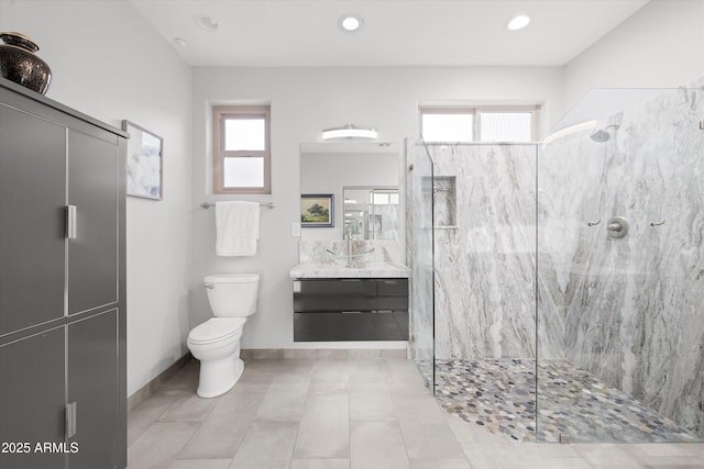 bathroom featuring tiled shower, vanity, toilet, and plenty of natural light