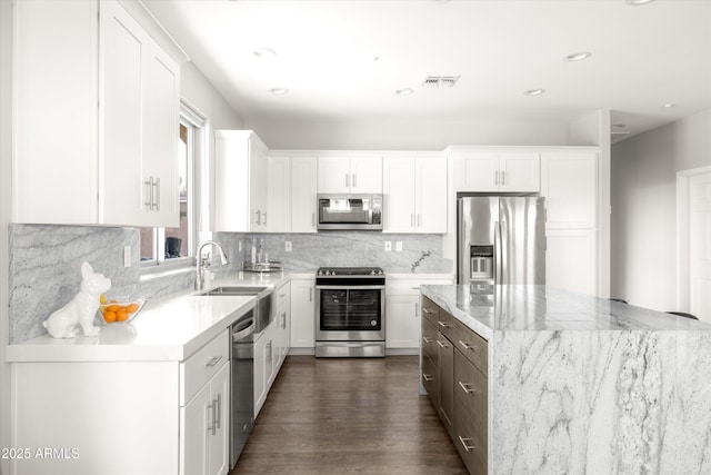 kitchen featuring backsplash, sink, light stone countertops, appliances with stainless steel finishes, and white cabinetry