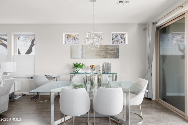 dining area with hardwood / wood-style floors and a notable chandelier