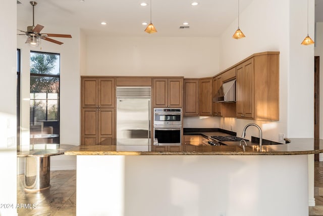 kitchen featuring a high ceiling, dark stone countertops, and pendant lighting