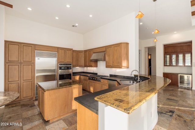 kitchen with hanging light fixtures, a towering ceiling, kitchen peninsula, beverage cooler, and sink