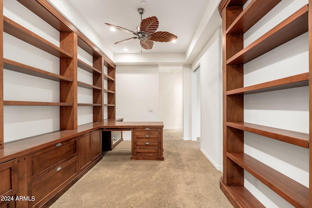 interior space with built in desk, ceiling fan, and light colored carpet