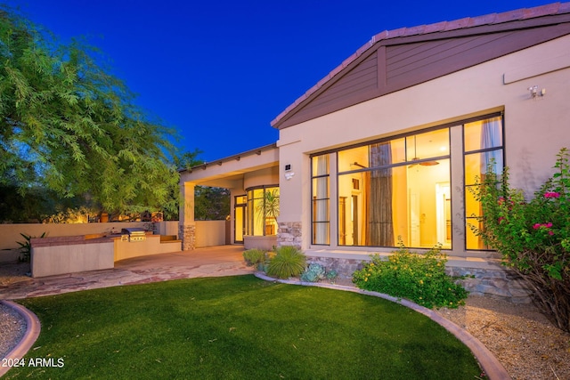 back house at night featuring a lawn