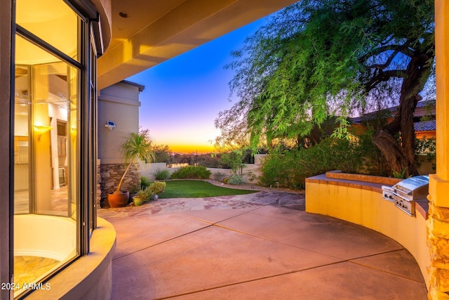 patio terrace at dusk featuring grilling area and exterior kitchen