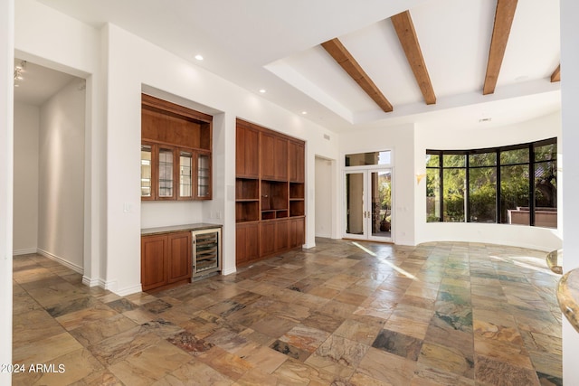 unfurnished living room with bar area, beverage cooler, and beam ceiling