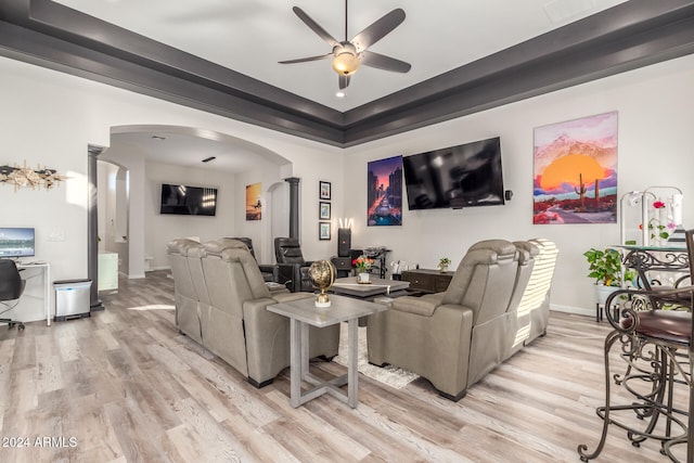 living room with a raised ceiling, ceiling fan, and light hardwood / wood-style flooring