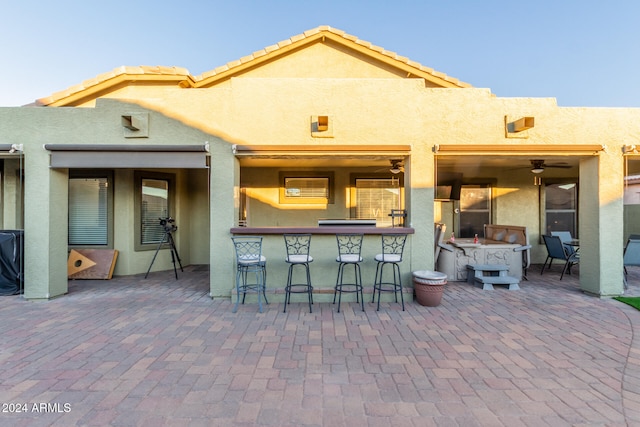 back of property featuring exterior bar and a patio