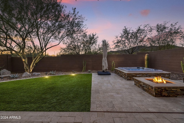 yard at dusk featuring a fire pit, a patio area, and an outdoor hot tub