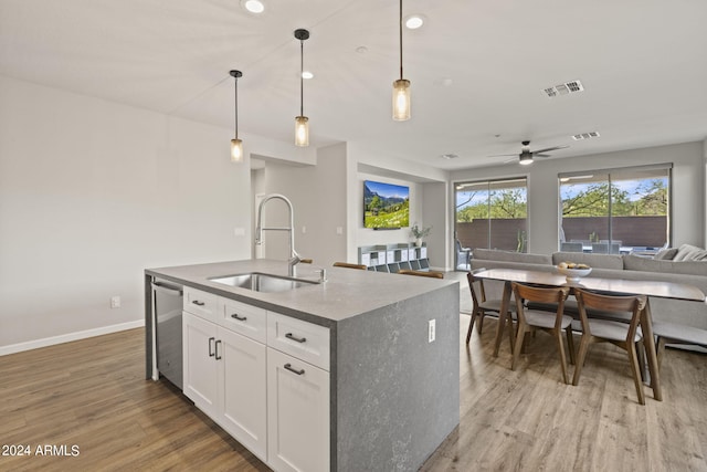 kitchen featuring an island with sink, sink, light hardwood / wood-style floors, pendant lighting, and white cabinetry