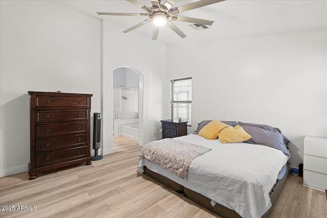 5026 S 235th Dr, Buckeye, AZ 85326 - bedroom featuring light wood-style flooring, connected bathroom, arched walkways, a ceiling fan, and high vaulted ceiling