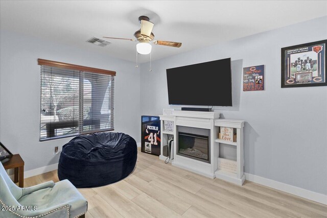 5026 S 235th Dr, Buckeye, AZ 85326 - living room featuring ceiling fan, wood finished floors, and a glass covered fireplace