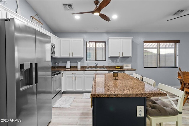 5026 S 235th Dr, Buckeye, AZ 85326 - kitchen featuring appliances with stainless steel finishes, a center island, ceiling fan, dark countertops, and a breakfast bar area