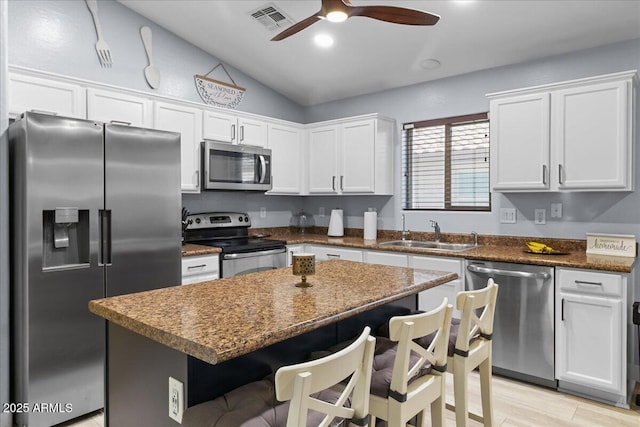 5026 S 235th Dr, Buckeye, AZ 85326 - kitchen with appliances with stainless steel finishes, lofted ceiling, white cabinets, a ceiling fan, and a breakfast bar