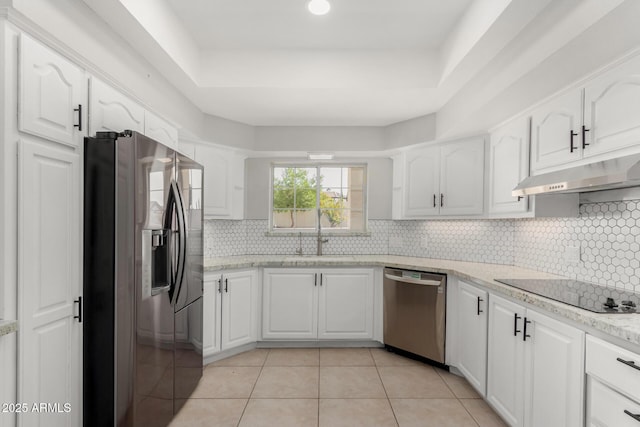 kitchen with under cabinet range hood, a sink, white cabinets, appliances with stainless steel finishes, and a raised ceiling