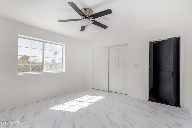 unfurnished bedroom featuring marble finish floor, a closet, and a ceiling fan