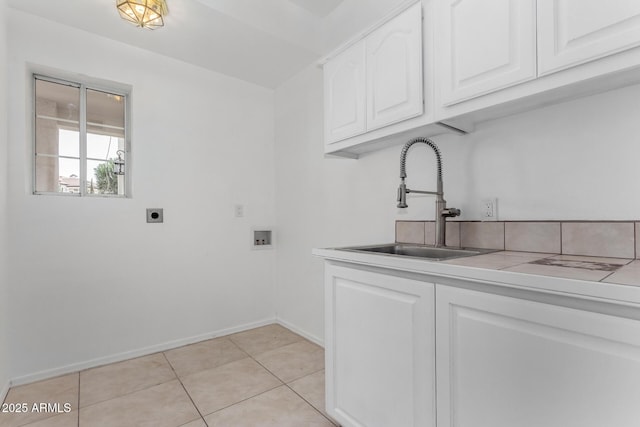 laundry room with light tile patterned floors, hookup for a washing machine, cabinet space, a sink, and electric dryer hookup