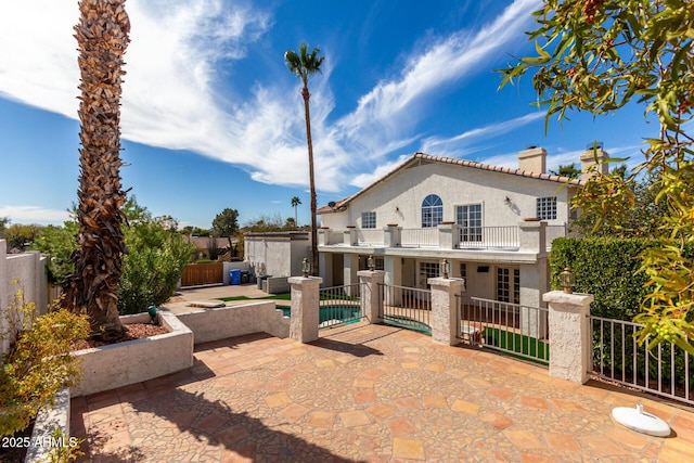 back of house featuring a fenced backyard, a balcony, a fenced in pool, stucco siding, and a patio area