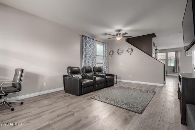 living area featuring a ceiling fan, baseboards, and wood finished floors