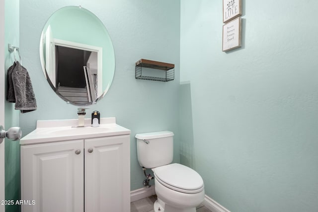 half bath featuring baseboards, toilet, and vanity