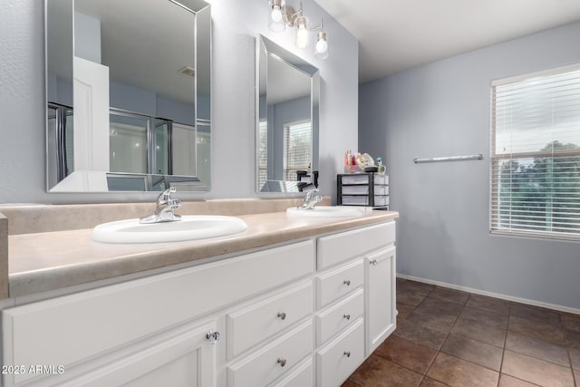 bathroom featuring double vanity, tile patterned floors, a shower stall, and a sink