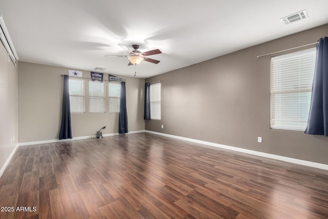 empty room featuring visible vents, baseboards, and dark wood finished floors